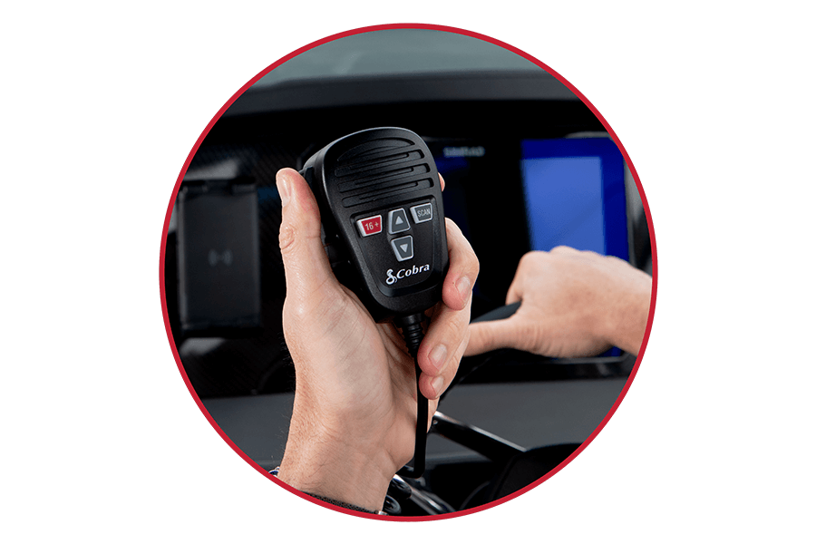 Hand holding a black Cobra BlueBound 1350 marine radio while steering a boat