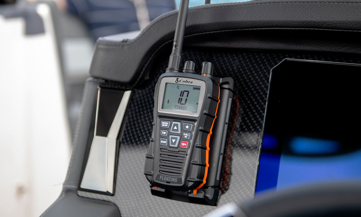 A black Cobra BlueBound 350 VHF marine radio clipped to a boat dashboard