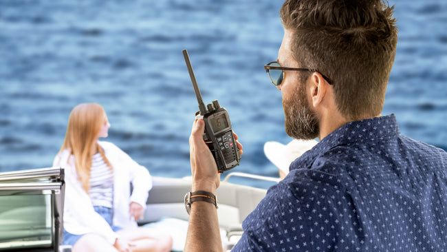 Man on boat speaks into Cobra handheld marine radio