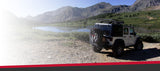 Off road vehicle drives along a rocky path by a mountain lake