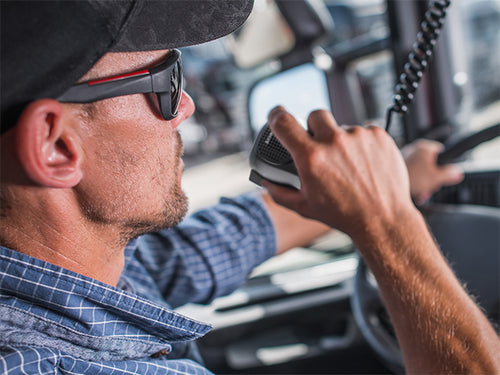 man driving in truck cab speaks into cb handset