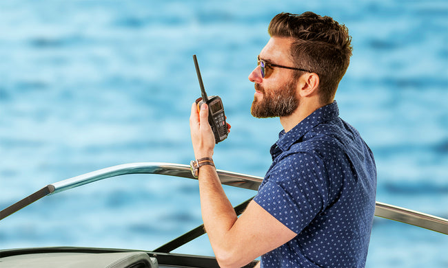 Man on a boat listens to Cobra BlueBound 150 VHF marine radio