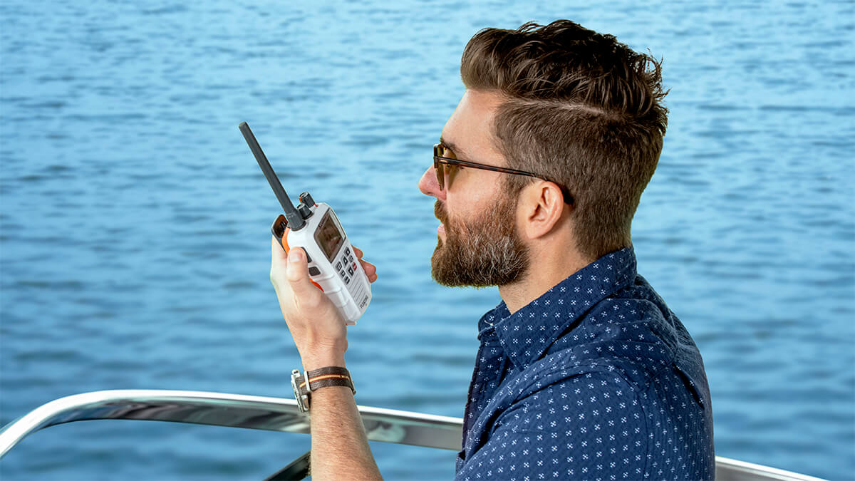Man on a boat using a white Cobra BlueBound 350 marine radio
