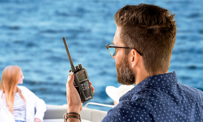 Man on a boat using a black Cobra BlueBound 350 marine radio