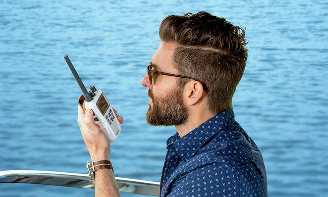 Man on a boat using a white Cobra BlueBound 350 marine radio