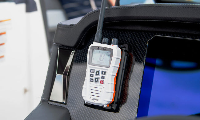 A white Cobra BlueBound 350 VHF marine radio clipped to a boat dashboard