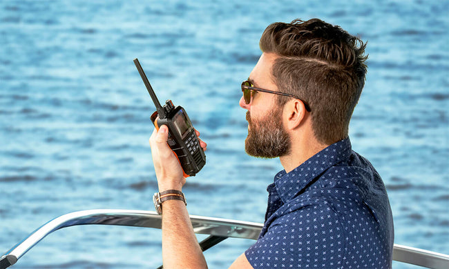 Man on a boat using a black Cobra BlueBound 650 marine radio