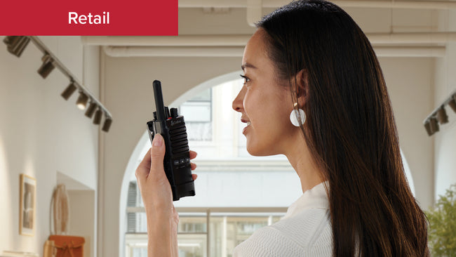 A fashionable manager in a bright boutique store calls to the back using Cobra PX650 business radio